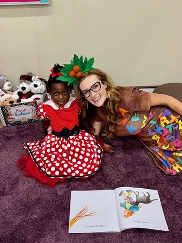 Women and child sitting on floor reading a book